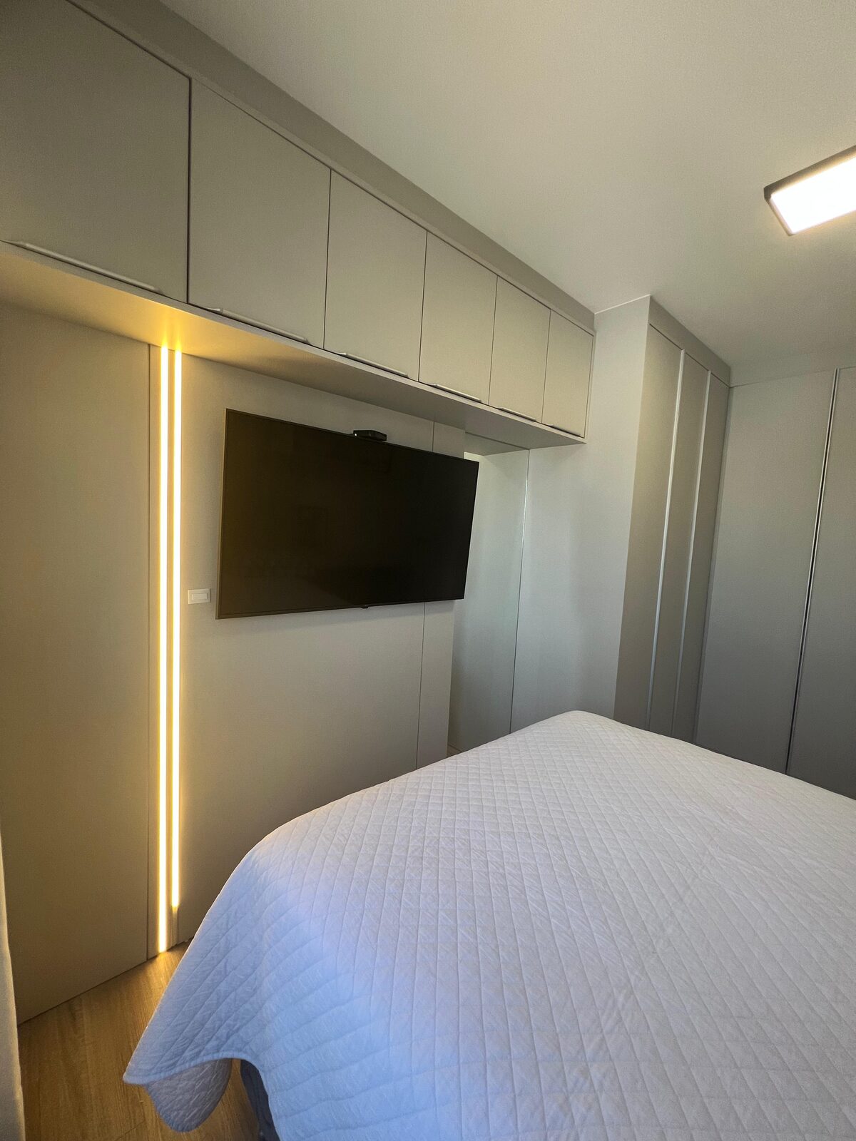 Dormitório planejado com armários aéreos e iluminação em LED